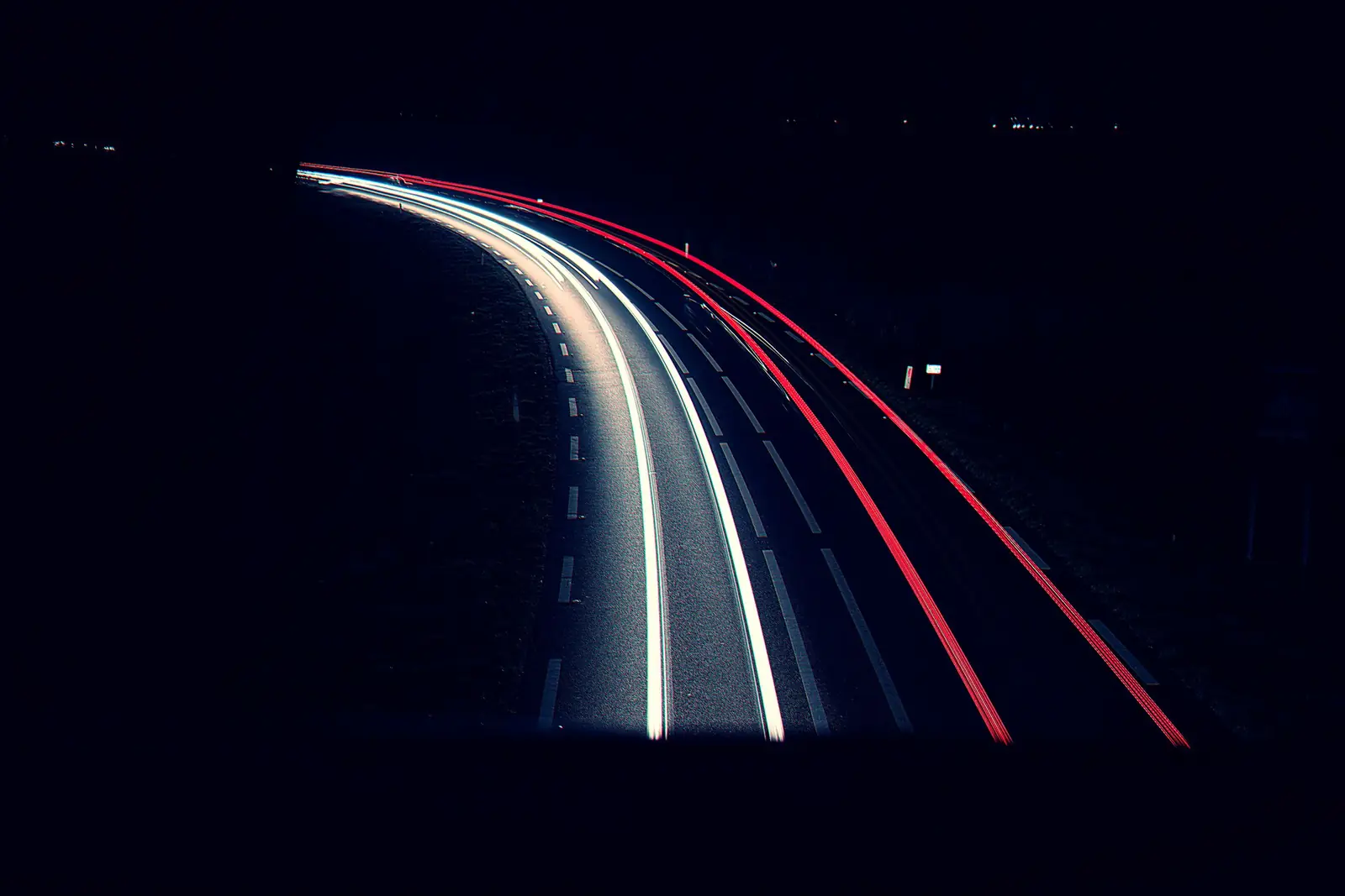 Lichtspuren von Autos auf einer kurvigen Straße bei Nacht